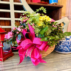 Arrangement of flowers with a pink bow on a bench