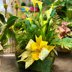 Floral arrangement with yellow flowers and a checkered ribbon in a garden setting