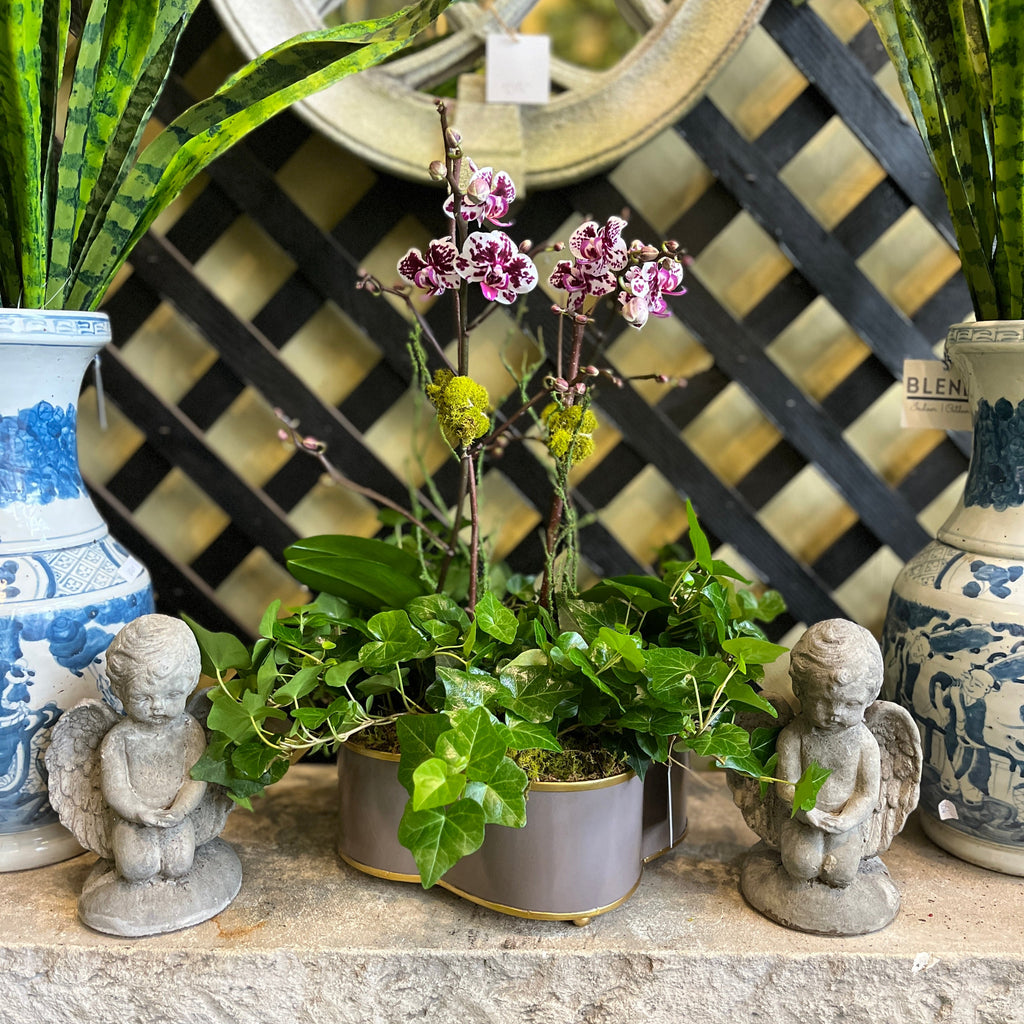 Decorative table with planted orchids, statues, and a decorative mirror.