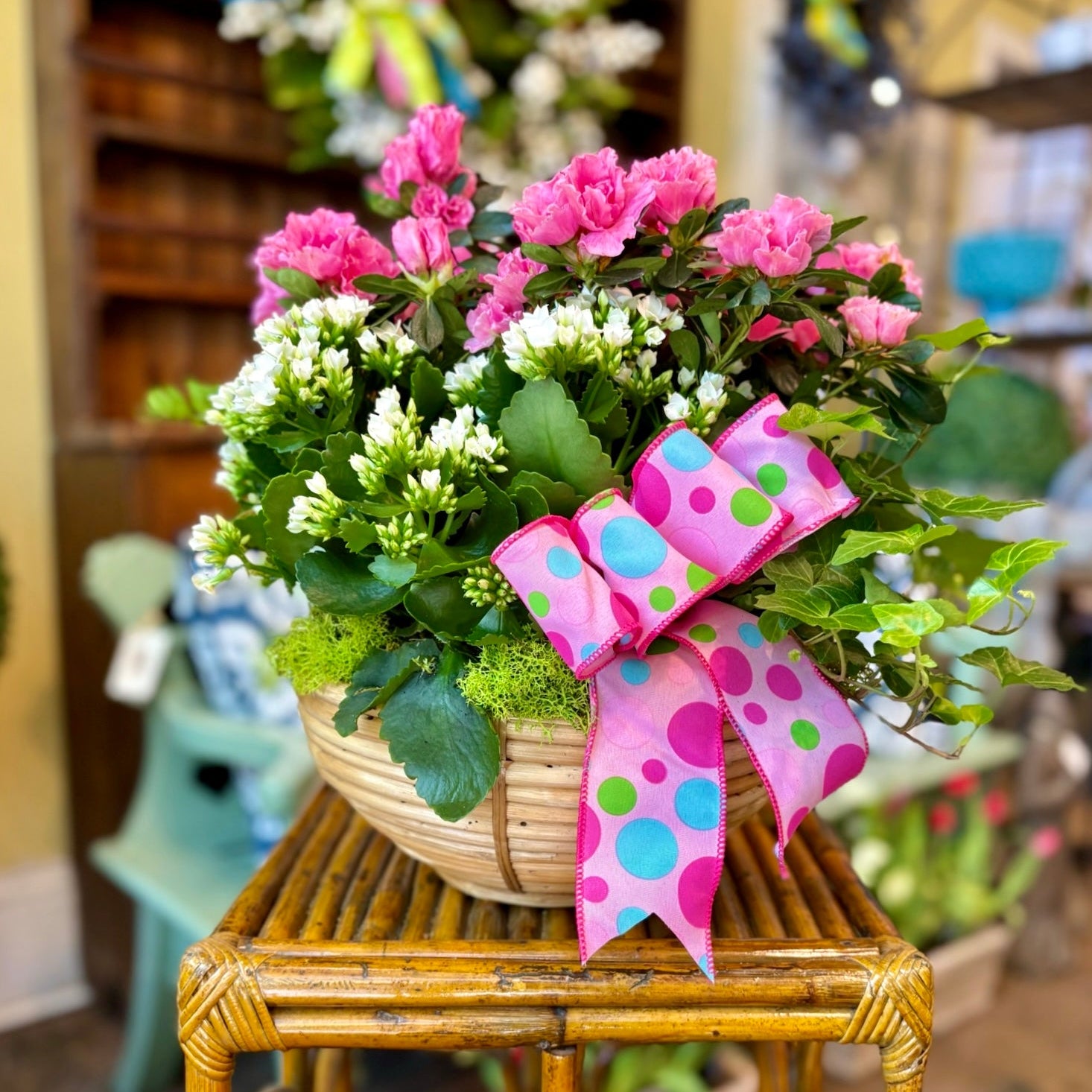 Floral arrangement with a polka dot ribbon on a wooden stool in a store setting