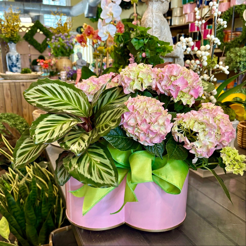 Decorative floral arrangement with pink flowers and green leaves in a store setting.