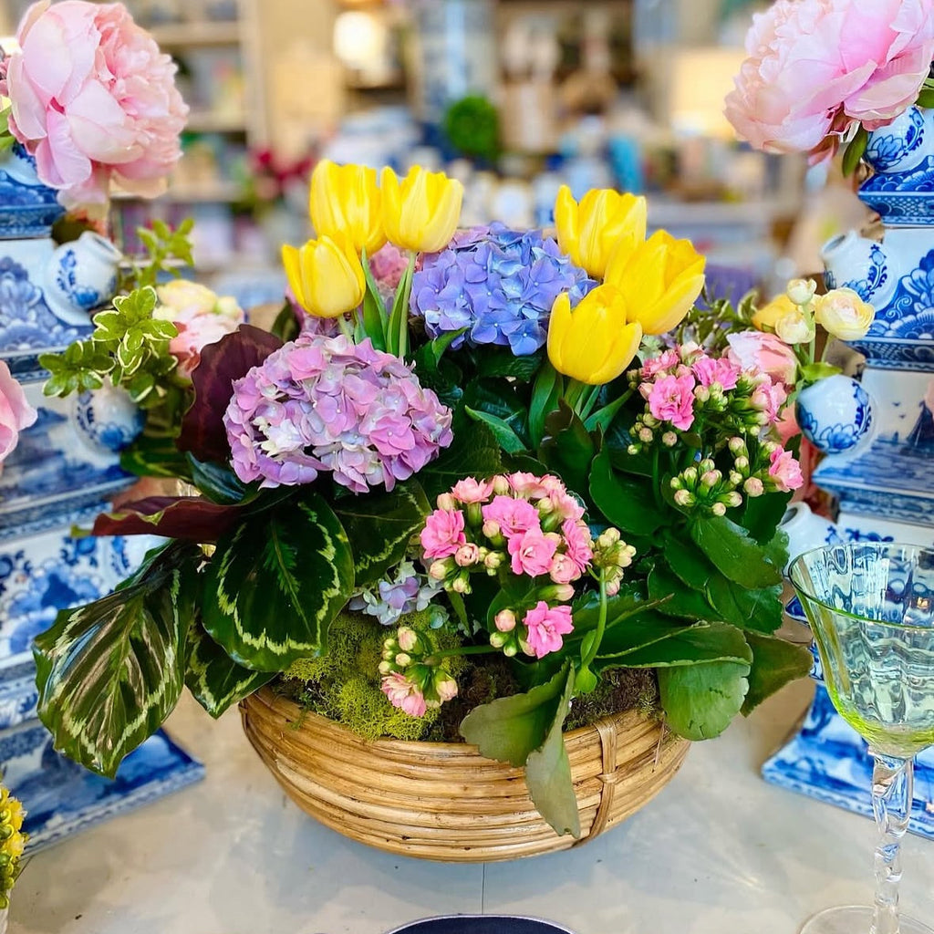 Arrangement of flowers with yellow tulips, pink and blue hydrangeas and yellow tulips in a store setting.
