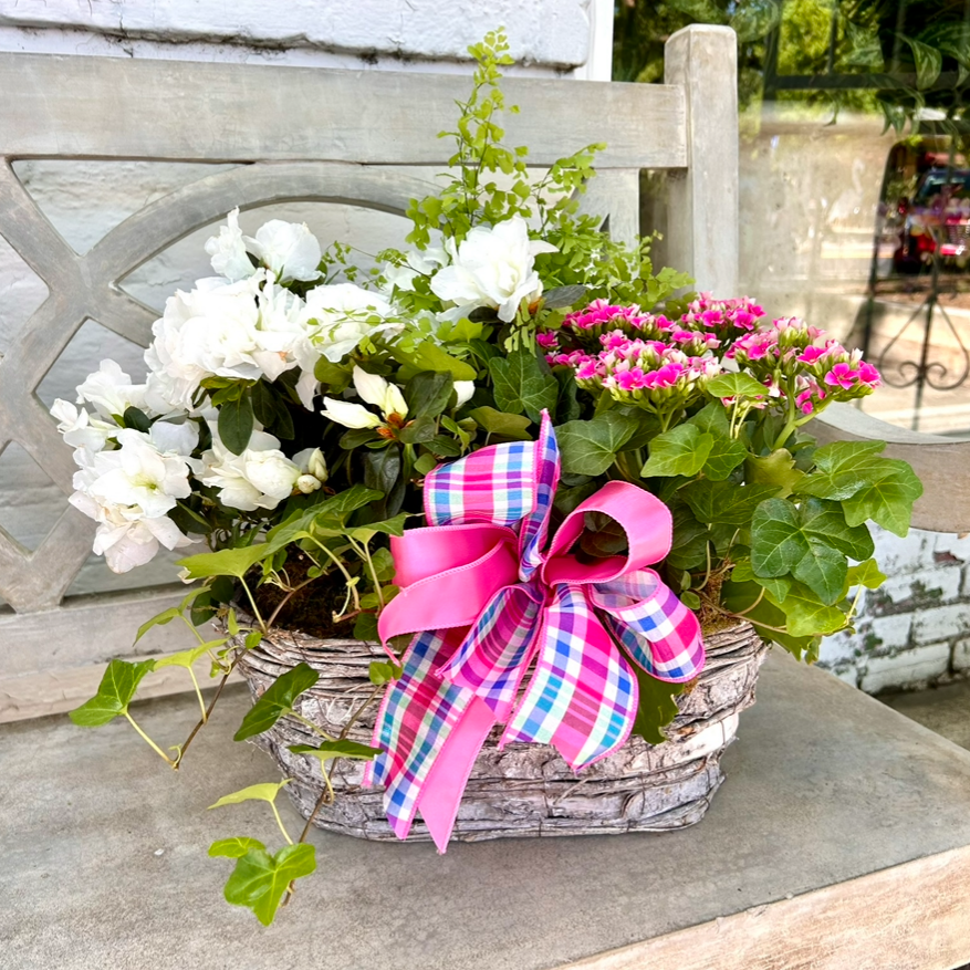 Floral arrangement in a basket with a pink bow on a concrete bench
